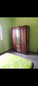 a bedroom with green walls and a bed and a cabinet at Le Séjour in Yaoundé