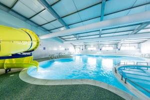 a large pool with a water slide in a building at The Palm - Large Static Caravan near Margate, Kent in Birchington