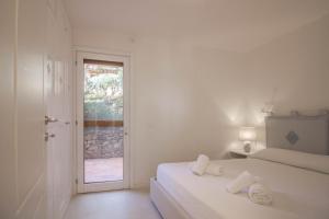 una camera bianca con un letto con due asciugamani di Portisco Bouganville Seaside Charm Flat W/ Veranda a Marina di Portisco