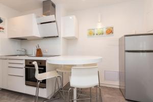 a white kitchen with a table and two stools at Apartments Tauzer in Mandre