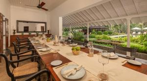 a dining room with a long table with chairs and a mirror at Uga Riva Negombo in Negombo