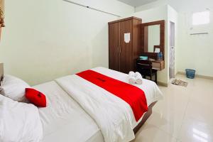 een slaapkamer met een bed met een rode en witte deken bij RedDoorz At Teratai Homestay Medan Amplas in Medan