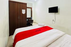 een slaapkamer met een rood en wit bed en een bureau bij RedDoorz At Teratai Homestay Medan Amplas in Medan