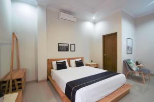 een slaapkamer met een groot wit bed en een stoel bij Cendhani Raras Residence in Demangan
