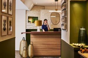 a woman talking on a cell phone at a counter at Hôtel Bordeaux Clémenceau by Happyculture in Bordeaux