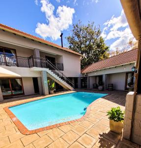 a swimming pool in front of a house at Solo Gracia Guesthouse in Bloemfontein