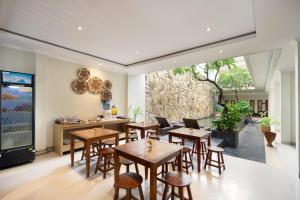 a restaurant with wooden tables and chairs and a large window at Angkul Angkul Segara Beach Kuta by Kamara in Kuta