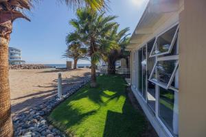 a house on the beach with palm trees next to it at Waterfront Cottage B3 in Swakopmund