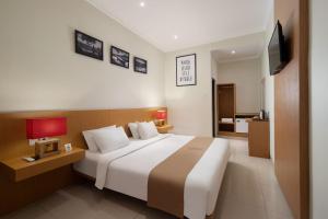 a hotel room with a large bed and a television at Angkul Angkul Segara Beach Kuta by Kamara in Kuta