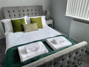 a bed with green and white pillows on it at M1 Link 2 bed house up to 4 people, free parking,wifi,M1,transport links,garden in Sutton in Ashfield