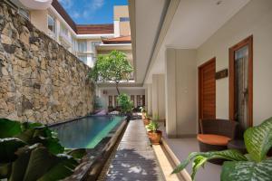 uma piscina interior com plantas e uma parede de pedra em Angkul Angkul Segara Beach Kuta by Kamara em Kuta