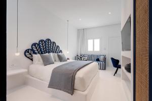 a white bedroom with a bed and a television at Croco Mykonos in Tourlos