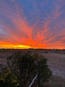 a sunset in the desert with a fence in the foreground at Silver Oaks Airbnb in Langebaan