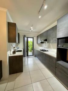 a large kitchen with gray cabinets and white tile floors at Charming 3 bedroom apartment with swimming pool in Flic-en-Flac