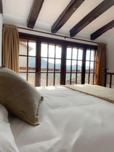 ein großes Bett mit Kissen in einem Zimmer mit Fenstern in der Unterkunft Casa Rural Cal Vellet del Priorat in La Vilella Baixa