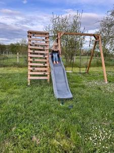a little girl sitting on a slide on a playground at Les Hauts de Grazac in Grazac