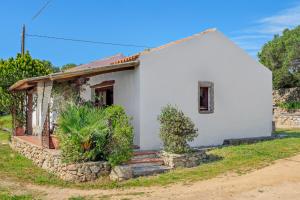 een klein wit huis met een stenen muur bij Stazzu Straetu in Olbia