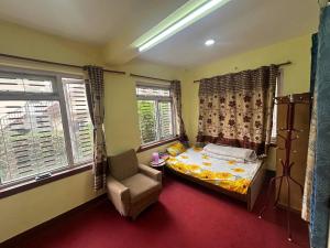 1 dormitorio con 1 cama, 1 silla y ventanas en Osho Gaurishankar Meditation Center, en Katmandú