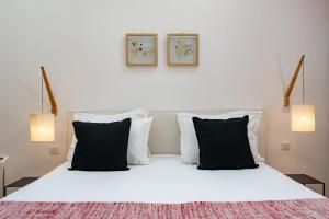 a bedroom with a white bed with black pillows at Maison d'Hôtes "Les Bulles Dorées" in Rilly-la-Montagne