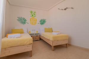 ein Schlafzimmer mit zwei Betten und einem Ananasschild an der Wand in der Unterkunft Villa Piña in Corralejo + 44 Fotos