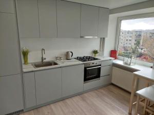 a kitchen with white cabinets and a sink and a window at Central w/free parking & Netflix in Vilnius