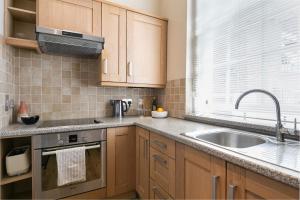 a kitchen with wooden cabinets and a sink and a window at Small sun lit studio minutes from Kings Cross station in London