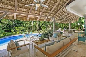 an outdoor patio with chairs and a swimming pool at 5-Bedroom Pool Villa for up to 10 people in Puntacana Resort & Club in Punta Cana