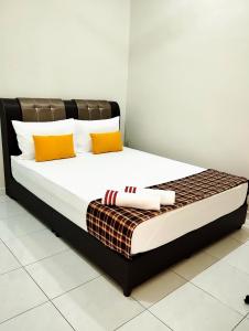 Una cama con almohadas naranjas y blancas. en Mukmin 2 Stay en Melaka