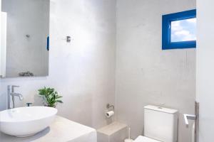 a white bathroom with a sink and a toilet at Aegean Blue Santorini Perissa in Perissa