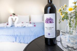 a bottle of wine sitting on a table next to a bed at Aegean Blue Santorini Perissa in Perissa