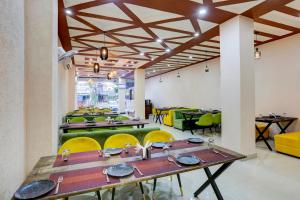 a dining room with tables and yellow chairs at Townhouse Hotel Selaqui Inn in Jhājra