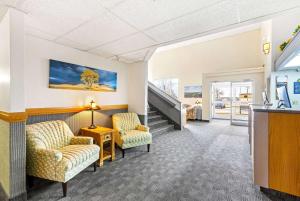 a living room with two chairs and a table and stairs at Days Inn by Wyndham Great Falls in Great Falls
