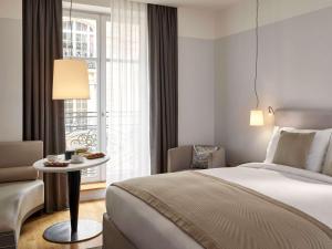 ein Hotelzimmer mit einem Bett, einem Tisch und einem Fenster in der Unterkunft Sofitel Paris Arc De Triomphe in Paris