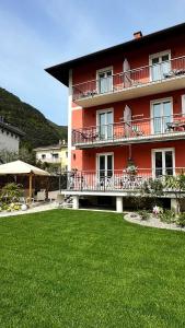 czerwony budynek z trawnikiem przed nim w obiekcie Garni Hotello Sport And Relax w mieście Riva del Garda