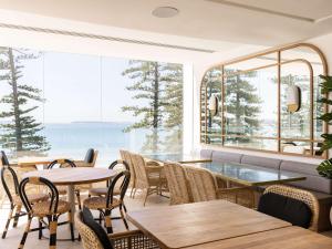 a restaurant with tables and chairs and a large window at Novotel Sydney Brighton Beach in Sydney
