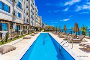 a swimming pool with lounge chairs and umbrellas at ONYX 2 Private Apartment in Sveti Vlas