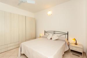 a white bedroom with a large bed with white sheets at Villetta Aurora in San Teodoro