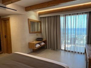 sypialnia z łóżkiem i dużym oknem w obiekcie Τhe Noverian Antama Organic Beach Resort Chania w mieście Agia Marina Nea Kydonias