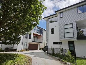 a white house with a driveway in front of it at Brand New & Central - 3 Bedrooms with 3 En suites in Auckland