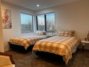 two beds in a room with two windows at Brand New & Central - 3 Bedrooms with 3 En suites in Auckland