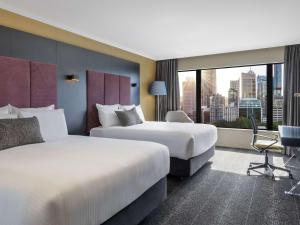 two beds in a hotel room with a view at Pullman Sydney Hyde Park in Sydney