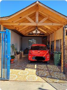un garage avec une voiture rouge garée sous un toit en bois dans l'établissement Casa aislada 1 piso Peñaflor-Malloco, à Talagante