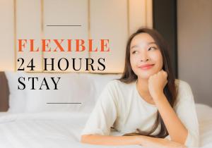 una joven sentada en una cama con el texto horario flexible en Citrus Suites Sukhumvit 6 by Compass Hospitality, en Bangkok