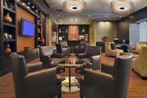 a waiting room with chairs and a table and a tv at Hyatt Regency O'Hare Chicago in Rosemont