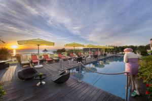 a woman standing on a deck next to a swimming pool at Hotel Kaiserhof Heringsdorf in Heringsdorf