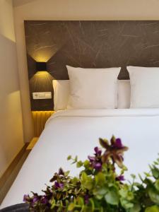 Una cama con sábanas blancas y flores púrpuras. en Hotel Casa Gardenia, en Barcelona