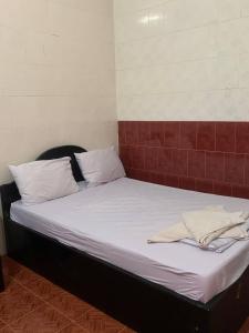 uma cama com lençóis brancos e almofadas num quarto em Ditar Guest House S em Battambang
