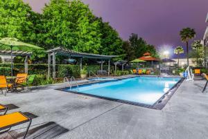 una piscina por la noche con mesas y sombrillas en La Quinta by Wyndham Tomball, en Tomball