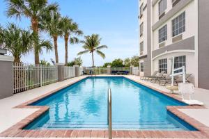 a swimming pool in front of a building with palm trees at La Quinta by Wyndham Ft. Pierce in Fort Pierce