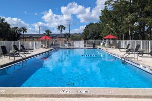 uma grande piscina azul com cadeiras e guarda-sóis em Quality Inn Gainesville I-75 em Gainesville